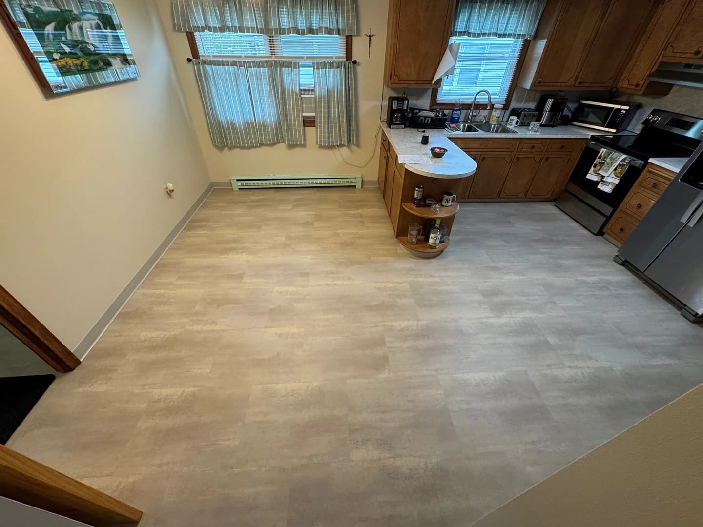 Finished no-grout LVT kitchen floor in New Britain, with gray cove base along the wall and flooring fitted beside the stove and refrigerator.