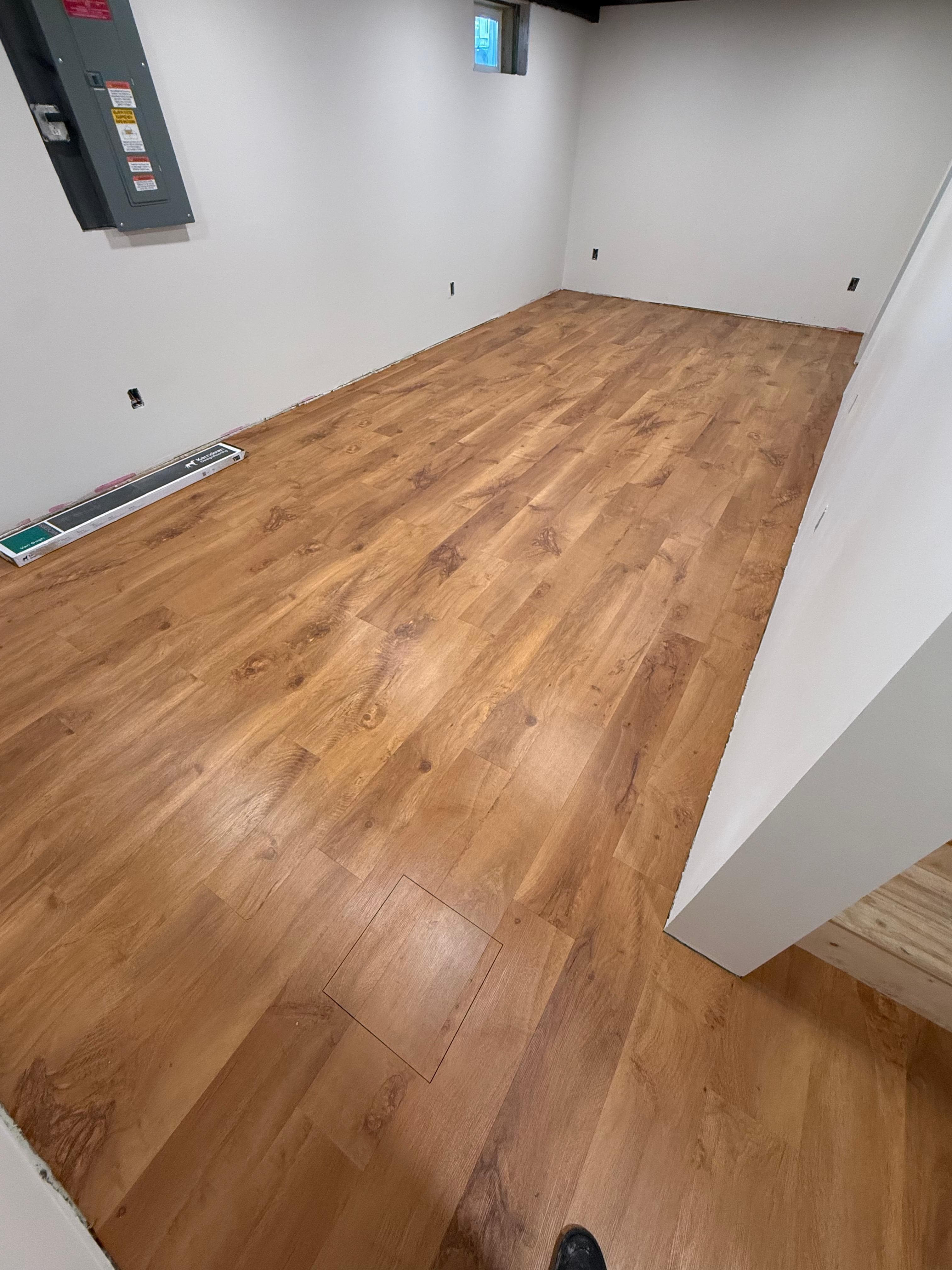 Finished basement room with warm wood-look plank flooring