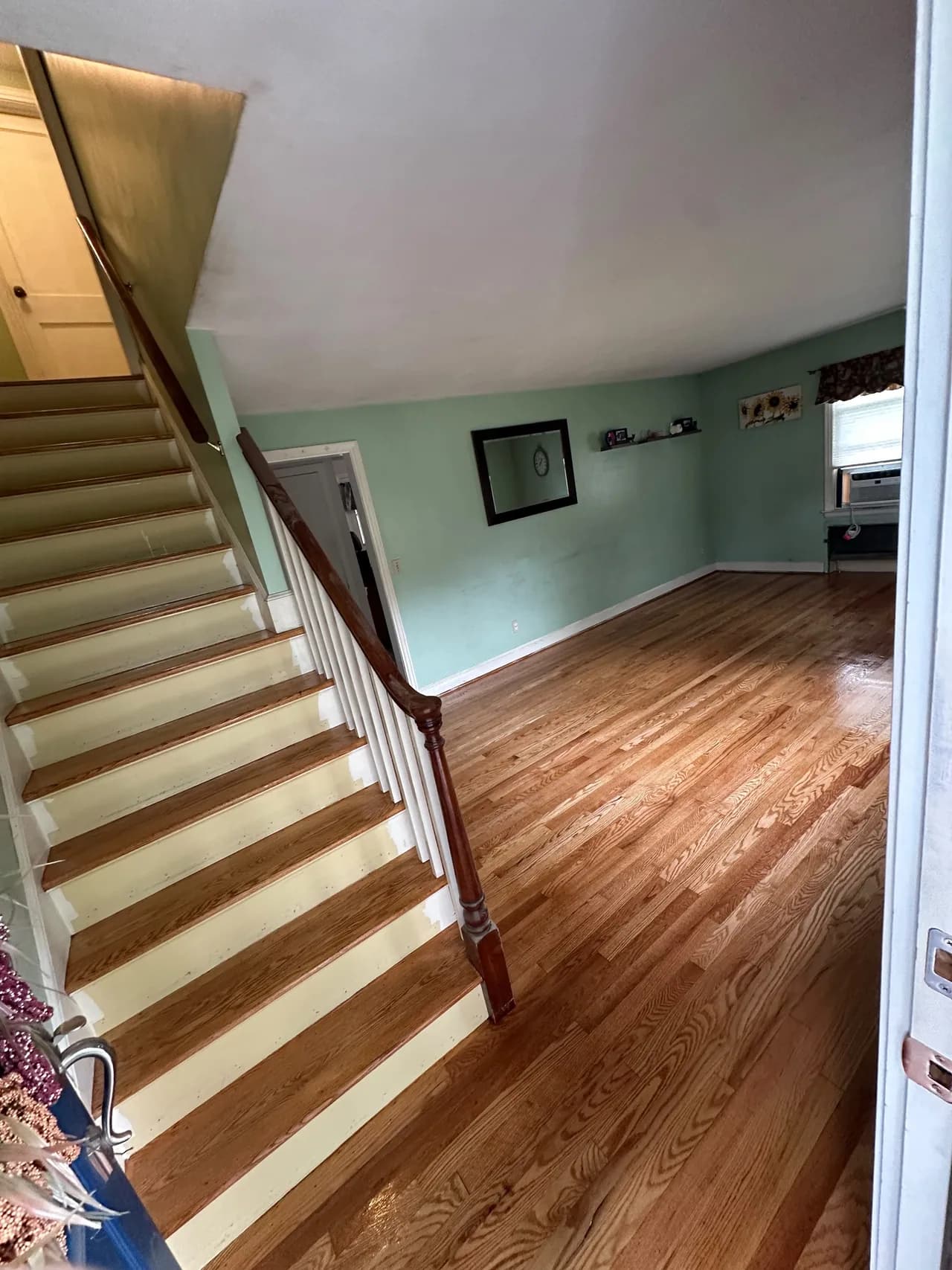 Wood flooring beside a staircase with matching wood treads and white risers.