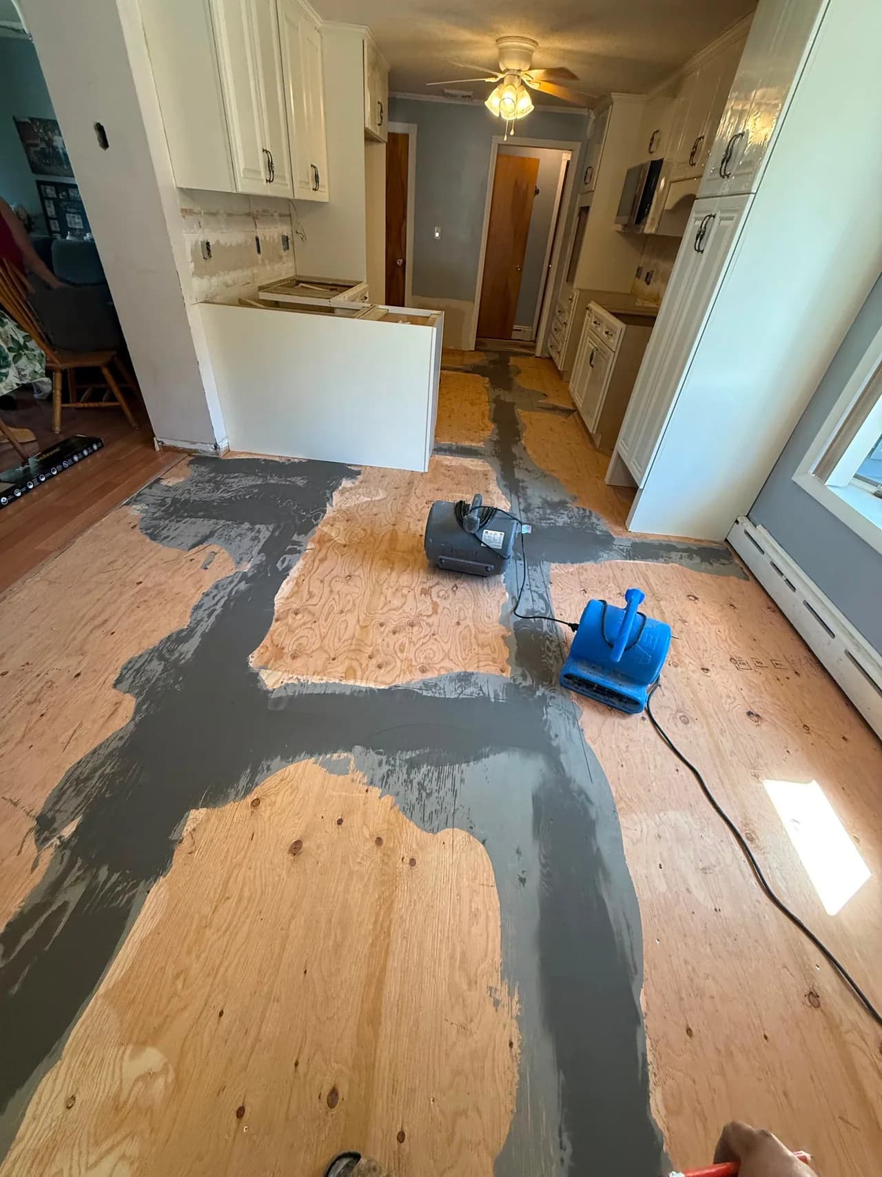 Exposed plywood subfloor with patched joints during kitchen floor preparation.