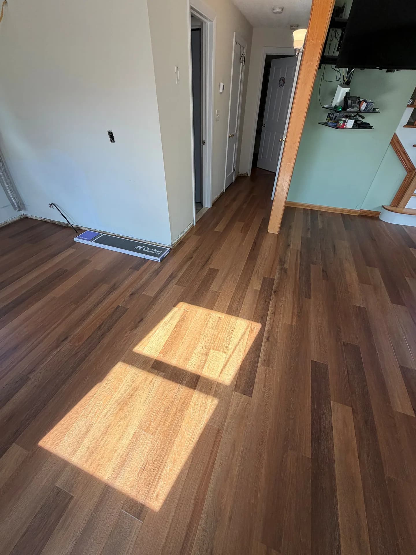 Installed wood-look luxury vinyl plank flooring continuing around a wall corner and into the home's hallway.
