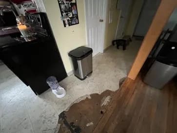 Damaged existing flooring beside the kitchen cabinets and hallway entrance before the new luxury vinyl plank floor.