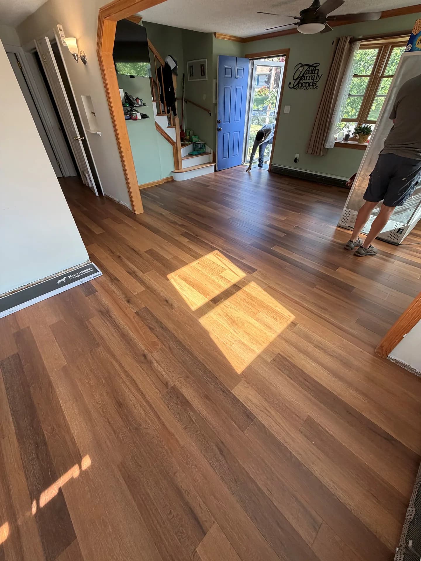 Wood-look LVP fitted across the living area beside the front entry, staircase, and connecting hallway in Bristol, CT.