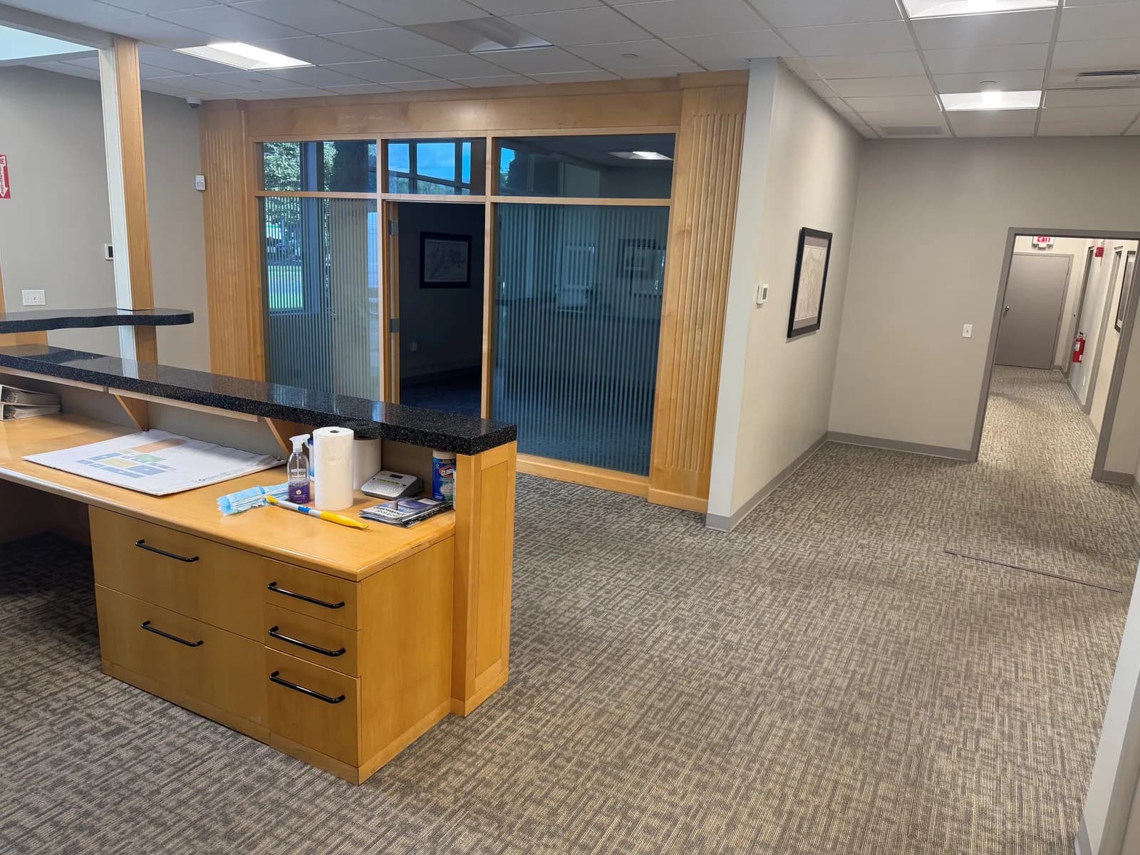 Patterned commercial carpet around a reception counter and through a connecting hallway in Hartford before LVP installation.
