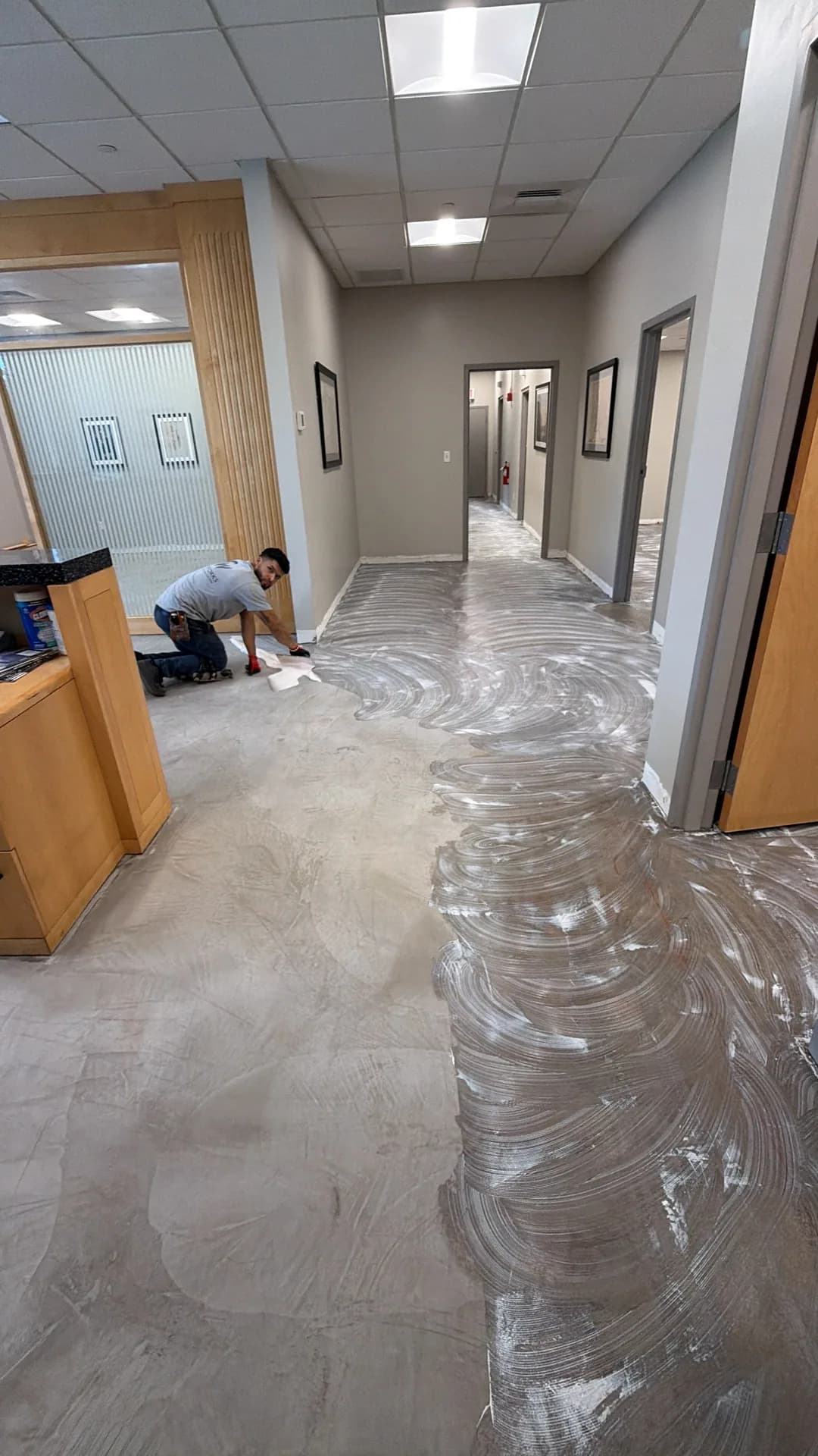 A worker applying a white surface coating to the exposed commercial floor after carpet removal in Hartford.