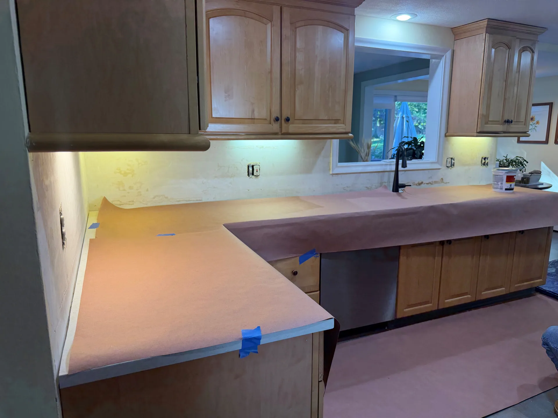 Paper-covered countertops and exposed backsplash walls around the kitchen pass-through.