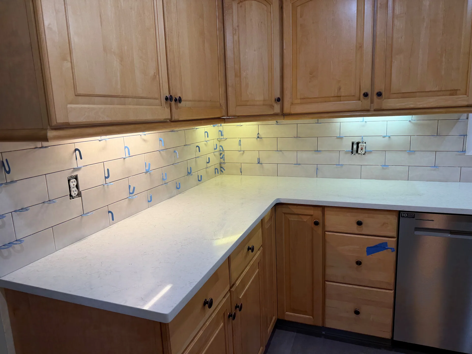 Horizontal rectangular tiles meeting at an inside corner, with blue joint spacers and an outlet cutout.