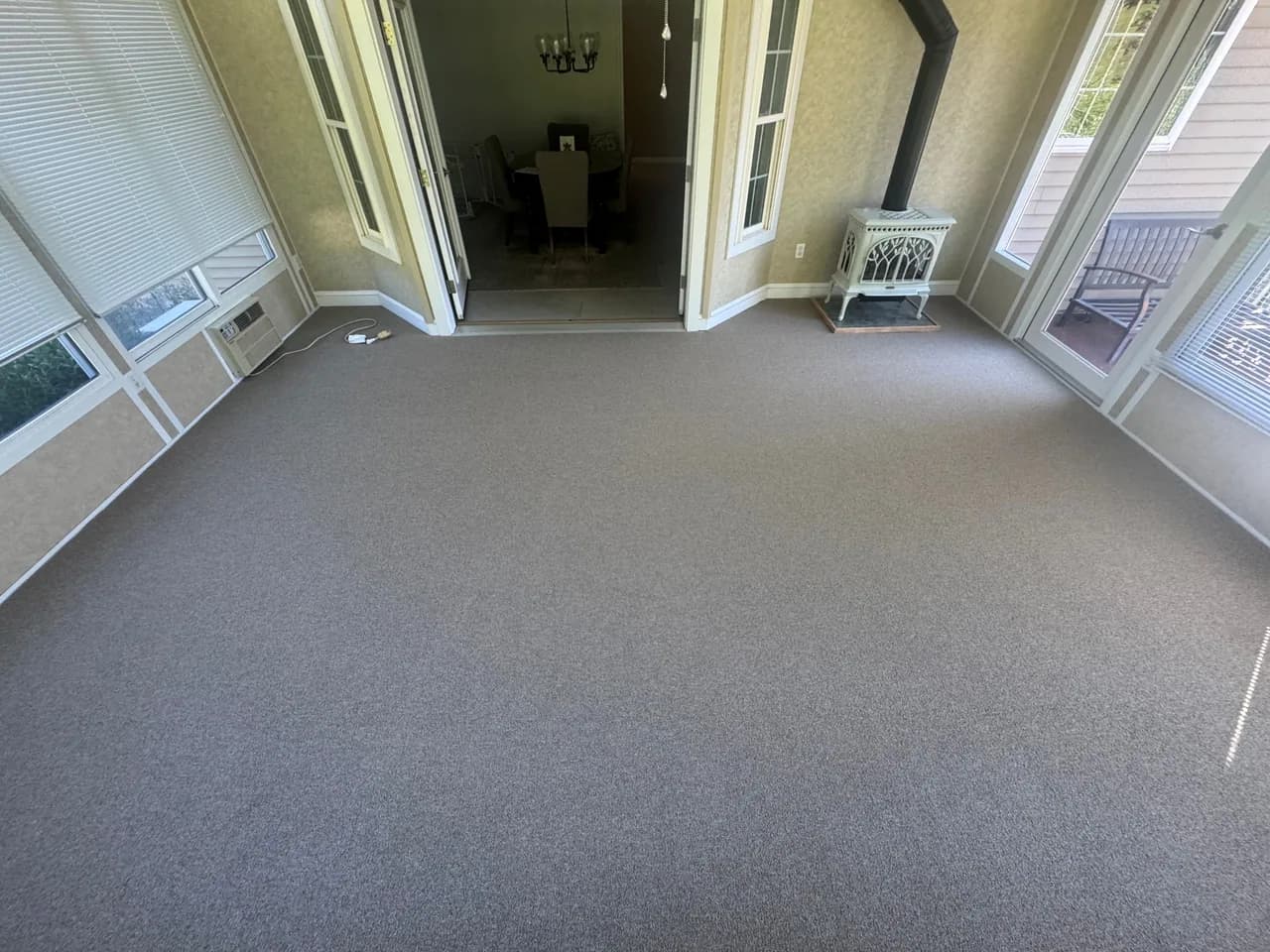 Neutral carpet fitted around a stove hearth and door thresholds in a sunroom.